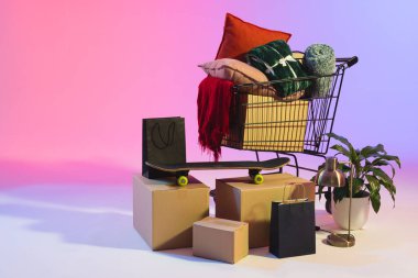 Alışveriş sepeti, kutular, bitki ve fotokopi alanı neon mor arka planda. Siber Pazartesi, Kara Cuma, çevrimiçi alışveriş, nakliye ve küresel bağlantılar kavramı.