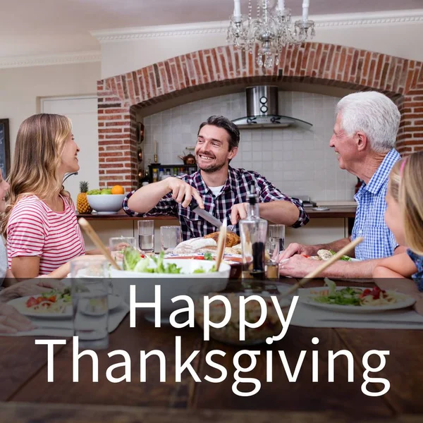 Happy thanksgiving text over happy caucasian family smiling at dinner table. Thanksgiving, harvest festival, american tradition, family and autumn celebration digitally generated image.