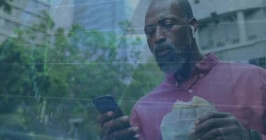 Afro-Amerikan bir adamın sokakta akıllı telefon kullanarak abur cubur yemesi üzerine veri işleme animasyonu. Küresel finans ve iş teknolojisi kavramı