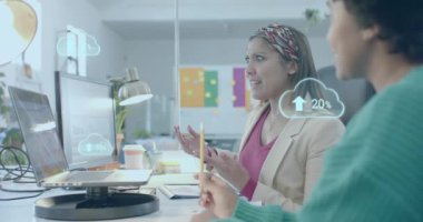 Bulut simgeleri, ofisteki bilgisayarda tartışan çeşitli bayan meslektaşlar üzerine veri yüklüyor. Günlük iş, veri, dijital arayüz, takım çalışması, ofis ve iletişim dijital olarak oluşturulmuş video.