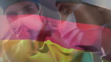 Hastanede ameliyat yapan erkek ve kadın cerrahlara karşı Alman bayrağı animasyonu. Tıbbi sağlık ve vatanseverlik kavramı