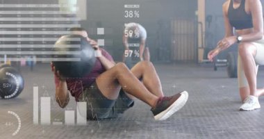 Çift ırklı kadın çalıştırıcı ve erkeğin spor salonunda topa çapraz antrenman yapması üzerine arayüzdeki verilerin animasyonu. Fitness, egzersiz, güç, veri, dijital arayüz ve dijital olarak üretilen video.