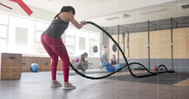 Beyaz bir kadının spor salonundaki savaş halatlarıyla çapraz eğitimle ilgili grafik işleme verilerinin animasyonu. Fitness, egzersiz, güç, veri, dijital arayüz ve dijital olarak üretilen video.
