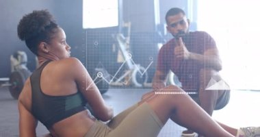 Spor salonunda tıp topu kullanan Afro-Amerikan erkek eğitmen ve kadın arayüzün animasyonu. Fitness, egzersiz, güç, veri, dijital arayüz ve dijital olarak üretilen video.