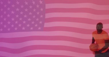 Amerikan bayrağının Afro-Amerikan erkek basketbolcu üzerinden top ile zıplaması. Spor, rekabet, bayrak, kimlik, milliyet ve vatanseverlik dijital olarak üretilen video.