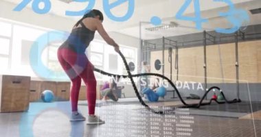 Beyazlı bir kadının spor salonundaki savaş halatlarıyla çapraz eğitimle ilgili arayüz işleme verilerinin animasyonu. Fitness, egzersiz, güç, veri, dijital arayüz ve dijital olarak üretilen video.