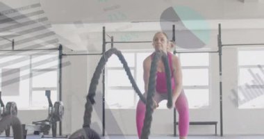 Beyazlı bir kadının spor salonundaki savaş halatlarıyla çapraz eğitimle ilgili arayüzdeki verilerin animasyonu. Fitness, egzersiz, güç, veri, dijital arayüz ve dijital olarak üretilen video.