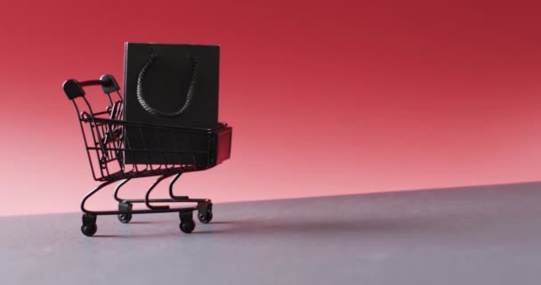 购物车上的黑色礼品袋视频 带有红色背景的复制空间 黑色星期五 网络星期一 网络购物 零售和航运概念 — 图库视频影像