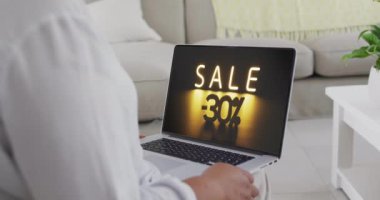 Çift ırklı bir kadın evde dizüstü bilgisayar kullanıyor, yavaş çekim. Çevrimiçi alışveriş, perakende ticaret, satış, iletişim ve dijital video arayüzü.