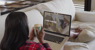 Çift ırklı bir kadın evde dizüstü bilgisayar kullanıyor, yavaş çekim. Çevrimiçi alışveriş, perakende ticaret, satış, iletişim ve dijital video arayüzü.