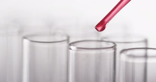 赤い液体が付いているガラス実験室のテスト管およびパイプのビデオおよび白い背景のコピースペース 化学のコンセプト — ストック動画