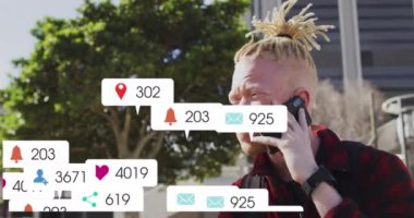 Numaraların animasyonu, bilgilendirme barlarındaki ikonlar, cep telefonuyla konuşan albino Afrikalı Amerikalı adam. Dijital bileşim, çoklu pozlama, iş, sosyal medya anımsatıcı ve teknoloji kavramı.