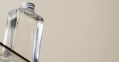Cam raftaki güzellik ürünleri şişesinin dikey videosu ve beyaz zemin üzerinde fotokopi alanı var. Sağlık ve güzellik, makyaj, güzellik ürünleri, renk ve hareket kavramı.