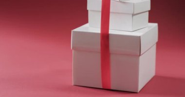 Kırmızı arkaplanlı kırmızı kurdeleli hediyeler yığını videosu. Noel, dekorasyon, gelenek ve kutlama konsepti.