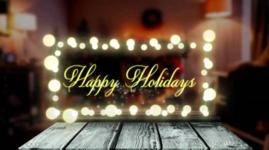 Mutlu bayram metinlerinin animasyonu peri ışıkları pankartıyla süslenmiş eve karşı ahşap tahta üzerine asılıyor. Noel şenliği ve tatil sezonu konsepti