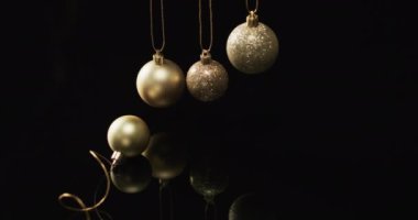 Siyah arka planda fotokopi alanı olan altın mücevher Noel süslerinin videosu. Noel, dekorasyon, gelenek ve kutlama konsepti.