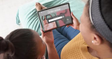 Afrika kökenli Amerikalı anne ve kız tablet kullanıyor, online el çantası alışverişi yapıyor, ağır çekimde. Perakende işi, satış, iletişim ve dijital arayüz oluşturulmuş video.
