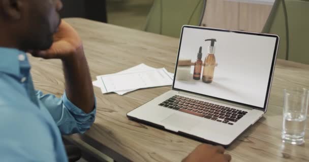 アフリカ系アメリカ人男性がノートパソコンを使い 美容製品のオンラインショッピング スローモーション 小売業 コミュニケーションおよびデジタル インターフェイスによってデジタル生成されるビデオ — ストック動画