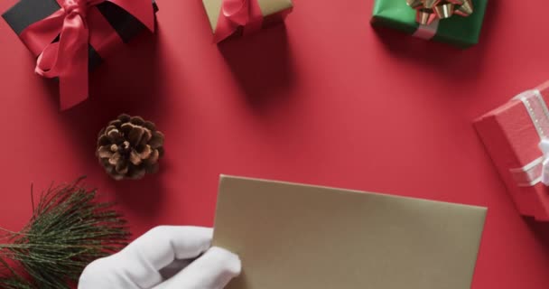 โอของซานตาคลอสถ อซองจดหมายส าตาลท ดลอกและของขว ญคร มาสบนพ นหล แดง มาส เคร — วีดีโอสต็อก