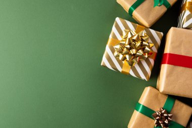 Kurdeleli Noel hediyeleri ve yeşil arka planda fotokopi alanı. Hediyeler, Noel, gelenek ve kutlama konsepti.