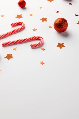 Kırmızı takılar, yıldızlar ve beyaz arka planda fotokopi alanı olan şeker kamışları. Noel, dekorasyon, gelenek ve kutlama konsepti.