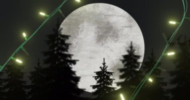 Sarı Noel ışıkları ağaçların üzerinde yanıp sönüyor ve Noel Baba kızakla dolunayı geçiyor. Noel, dekorasyon, gelenek ve dijital olarak üretilen video kutlaması.