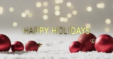 Karda parlak kırmızı Noel süsleri ve arka planda Bokeh ışıkları olan mutlu bayramlar mesajları. Noel, dekorasyon, gelenek, selamlama ve dijital olarak oluşturulan video kutlaması.