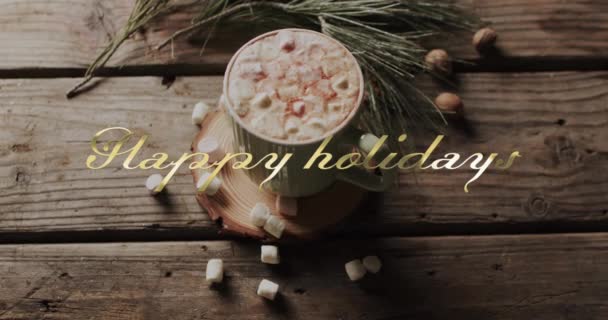 木の背景にマシュマロが付いているクリスマスのホット チョコレートの上の金の幸せな休日のテキスト クリスマス お祝いのデジタル生成ビデオ — ストック動画
