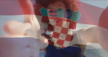 Hırvat bayrağının sahilde kamerayla konuşan melez bir kadının selfie videosunun üzerinde dalgalanması. Dijital bileşim, çoklu pozlama, özgürlük, hükümet, vatanseverlik ve teknoloji kavramı.