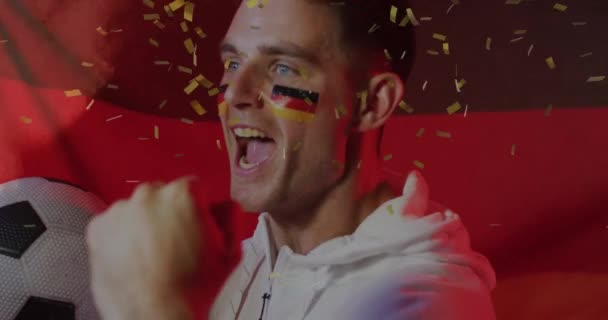 ドイツのフェイスペンキの旗を持つ白人男性サッカーファンを応援する金の菓子のアニメーション サポート スポーツデジタル生成ビデオ — ストック動画