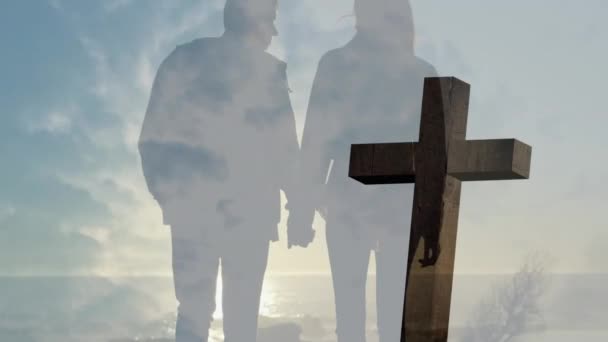 曇りの空のタイムラウンドに対する十字架のアニメーション 手を握っているカップルのリアビュー デジタル複合 複数の露出 十字架 トグルネスコンセプト — ストック動画