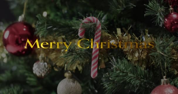 クリスマスツリーの装飾の上に黄色のメリークリスマステキスト クリスマス お祝いのデジタル生成ビデオ — ストック動画