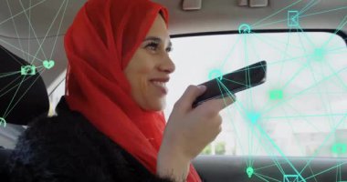 Arabadaki ses asistanını kullanarak tesettüre giren beyaz kadın üzerindeki ikon kürelerin animasyonu. Dijital bileşik, çoklu pozlama, iletişim, küreselleşme, ulaşım ve teknoloji.