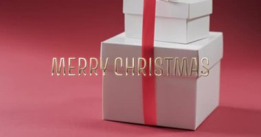 Kırmızı arka planda beyaz noel hediyeleri eşliğinde mutlu noeller mesajı. Noel, gelenek, selamlar ve dijital olarak oluşturulan video kutlaması.