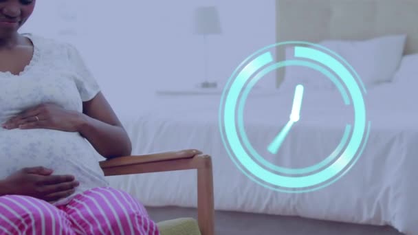 ハッピーな妊娠中のアフリカ系アメリカ人女性が座って腹を抱えている時計 セルフケア 平均余命 家庭生活がデジタル生成されたビデオ — ストック動画