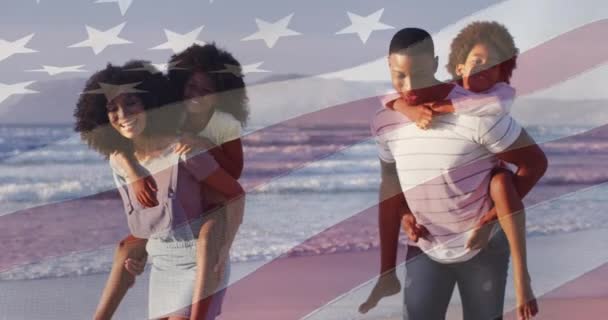 在非洲裔美国人夫妇的海滩上 美国国旗在他们的儿子和女儿之上飘扬 美国的爱国主义 夏季和多样性概念数码视频 — 图库视频影像