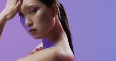 Siyah saçlı ve makyajlı bir Asyalı kadın yüzüne dokunuyor, kopyalama alanı, ağır çekim. Sağlık ve güzellik, makyaj, kadınlık kavramı, değiştirilmemiş.