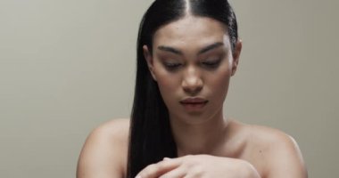 Siyah saçlı ve makyajlı melez bir kadın kameraya bakıyor, mekanı kopyalıyor, yavaş çekim yapıyor. Sağlık ve güzellik, makyaj, kadınlık kavramı, değiştirilmemiş..