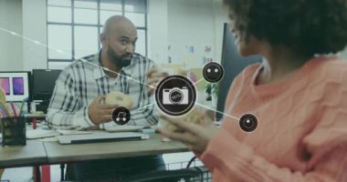 Masada çörek yerken tartışan farklı iş arkadaşlarının birbirine bağlı simgelerin canlandırılması. Dijital bileşik, çoklu pozlama, iletişim, yemek, ofis, müzik ve iş konsepti.