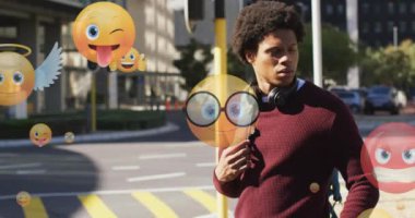 Çift ırklı bir adamın caddede yürürken ve kaydırırken birden fazla emoji animasyonu. Dijital bileşik, çoklu pozlama, duygu simgeleri, sosyal medya, soyut ve teknoloji kavramı.