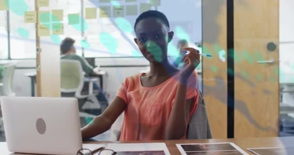 グラフ 地図のアニメーション オフィスに座っているアフリカ系アメリカ人女性の笑顔の数字の変化 デジタル複合 複数の露出 レポート ビジネス グローバルコンセプト — ストック動画