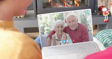 Kafkasyalı mutlu çift ve üst düzey ebeveynler Noel 'de dizüstü bilgisayar kullanırken, yavaş çekimde. İletişim, aile, arkadaşlar, Noel, kutlama, birliktelik, gelenek ve yaşam tarzı, değiştirilmemiş.