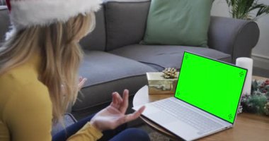 Kafkasyalı mutlu bir kadın, yeşil ekranlı, ağır çekimde, yılbaşı bilgisayarlı video görüşmesi yapıyor. İletişim, aile, arkadaşlar, Noel, kutlama, birliktelik, gelenek ve yaşam tarzı, değiştirilmemiş.