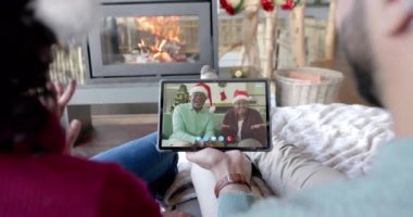 Mutlu çiftler ve yaşlı aileler Noel tabletinden aranıyorlar, yavaş çekim. İletişim, aile, arkadaşlar, Noel, kutlama, birliktelik, gelenek ve yaşam tarzı, değiştirilmemiş.