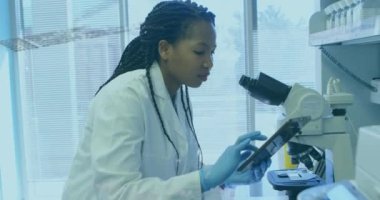 Laboratuvarda mikroskop kullanarak Afrika kökenli Amerikalı kadın bilim adamı üzerinde veri işleme animasyonu. Tıbbi araştırma ve bilim teknolojisi kavramı
