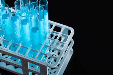 Laboratuvar deney tüplerini mavi sıvıyla kapatın ve siyah arka planda kopyalayın. Laboratuvar, bilim, araştırma ve kimya konsepti.
