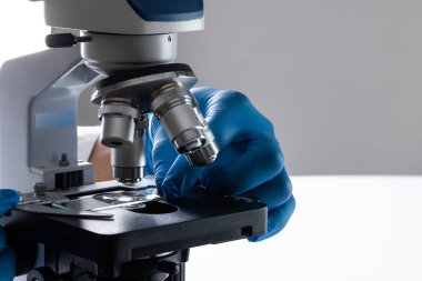 Laboratuvar mikroskobu kullanarak eldiveni kapat ve beyaz arkaplandaki boşluğu kopyala. Laboratuvar, bilim, araştırma ve kimya konsepti.