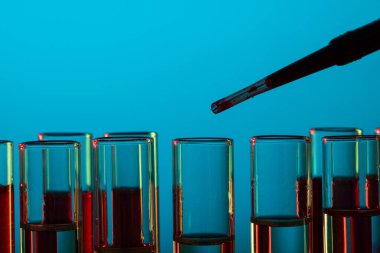 Laboratuvar test tüplerini ve mavi arka planda fotokopi alanı olan pipetleri kapatın. Laboratuvar, bilim, araştırma ve kimya konsepti.