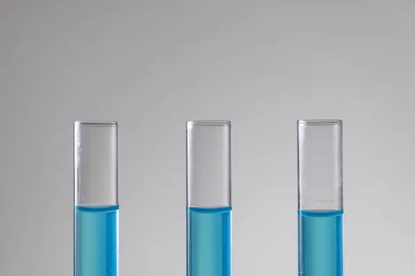 Close up of laboratory test tubes with blue liquid and copy space on white background. Laboratory, science, research and chemistry concept.