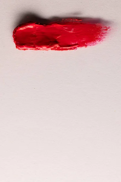 Vertical image of beauty product red lipstick smudge with copy space on white background. Health and beauty, beauty product, make up and colour concept.